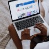 A woman browsing digital designs on a laptop while sitting comfortably at home.